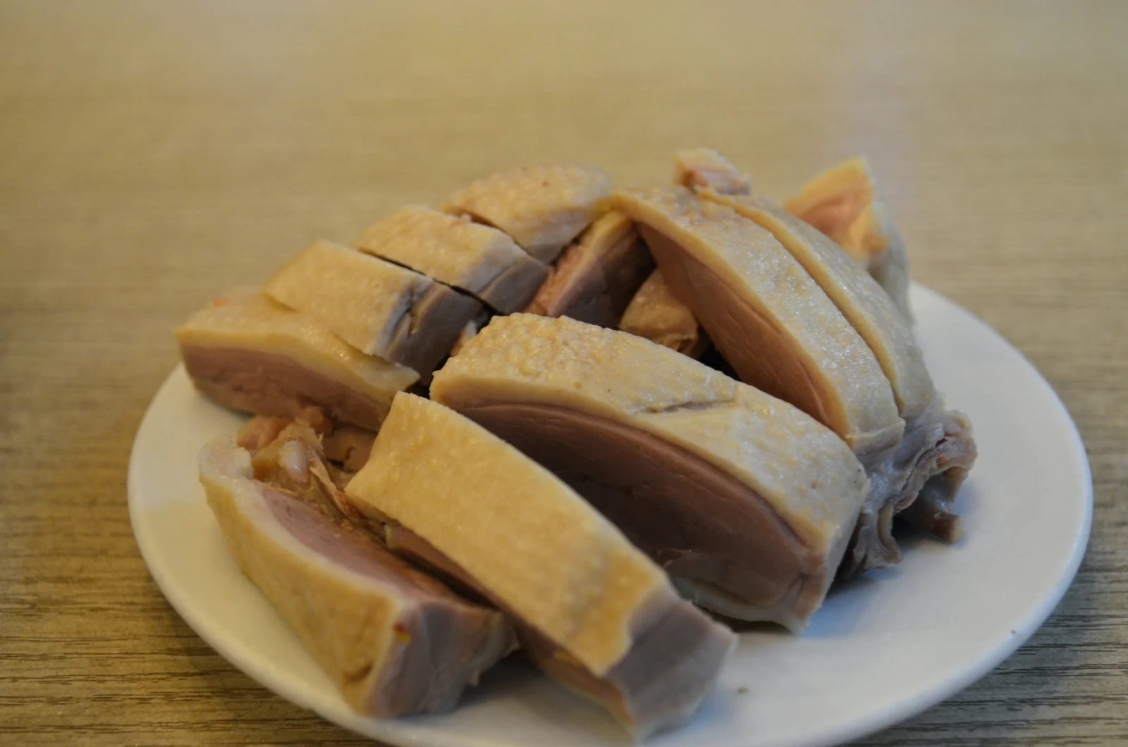 Slices of Nanjing salted duck with pale golden skin on a white plate