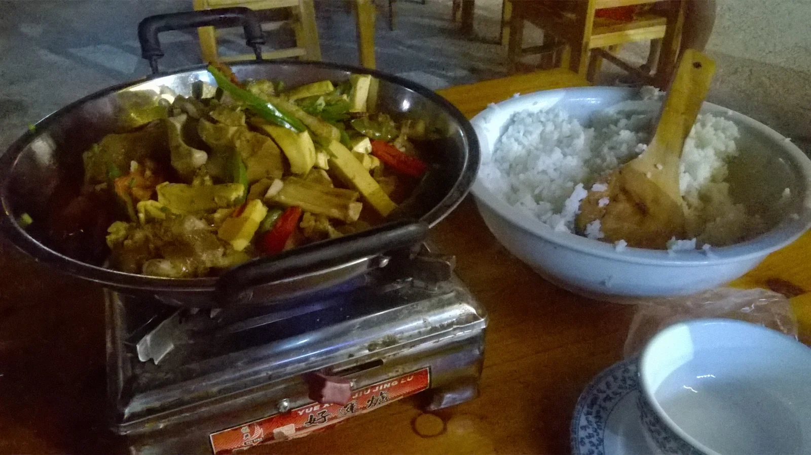 A pan of Zhangjiajie sanxiaguo mixed pot beside a bowl of rice