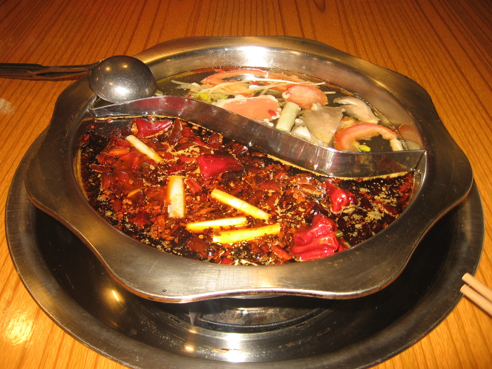 A divided Chongqing hot pot with vivid red chili broth and a clear broth section
