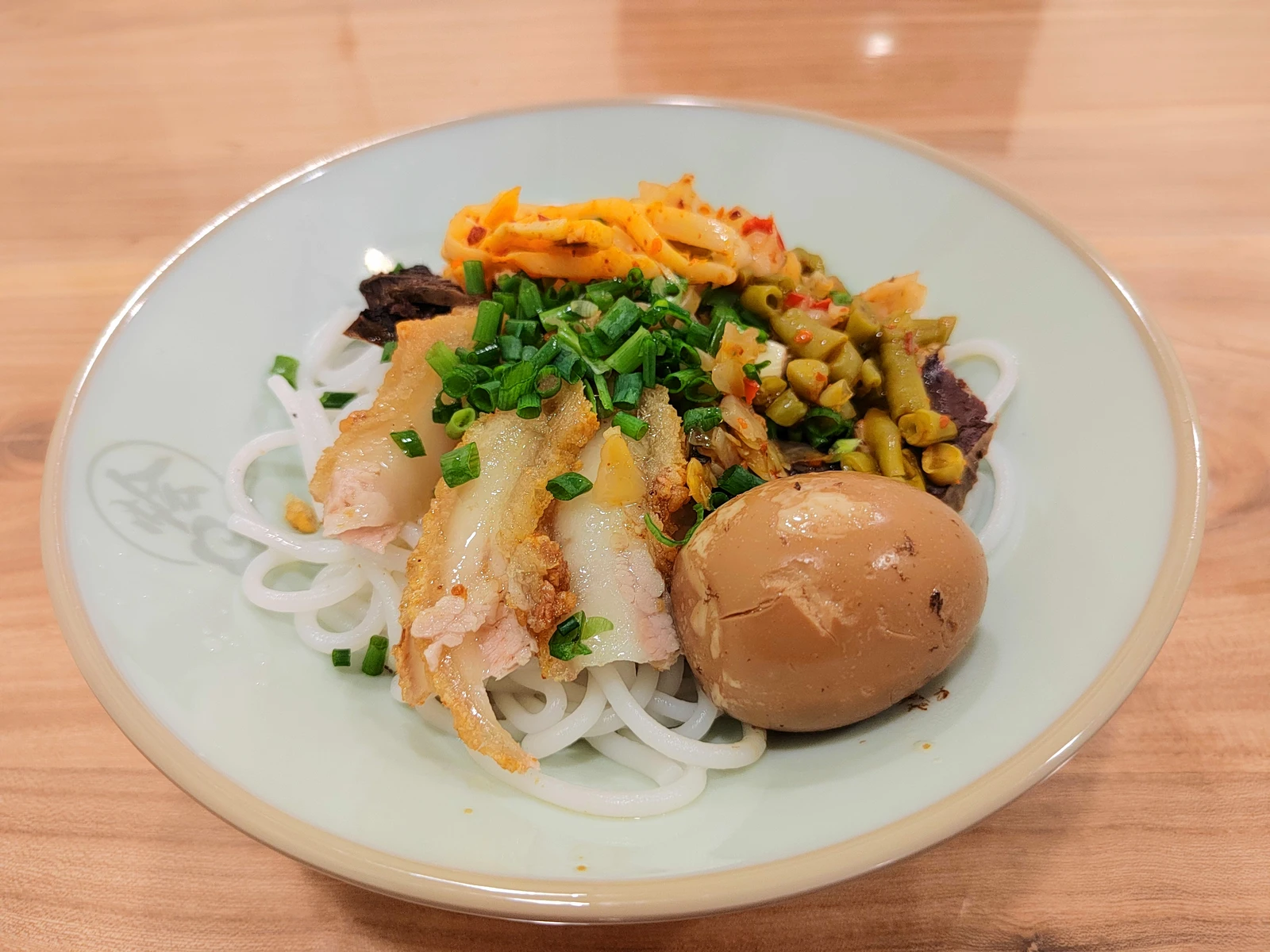Guilin rice noodles with braised toppings and vegetables in a white bowl