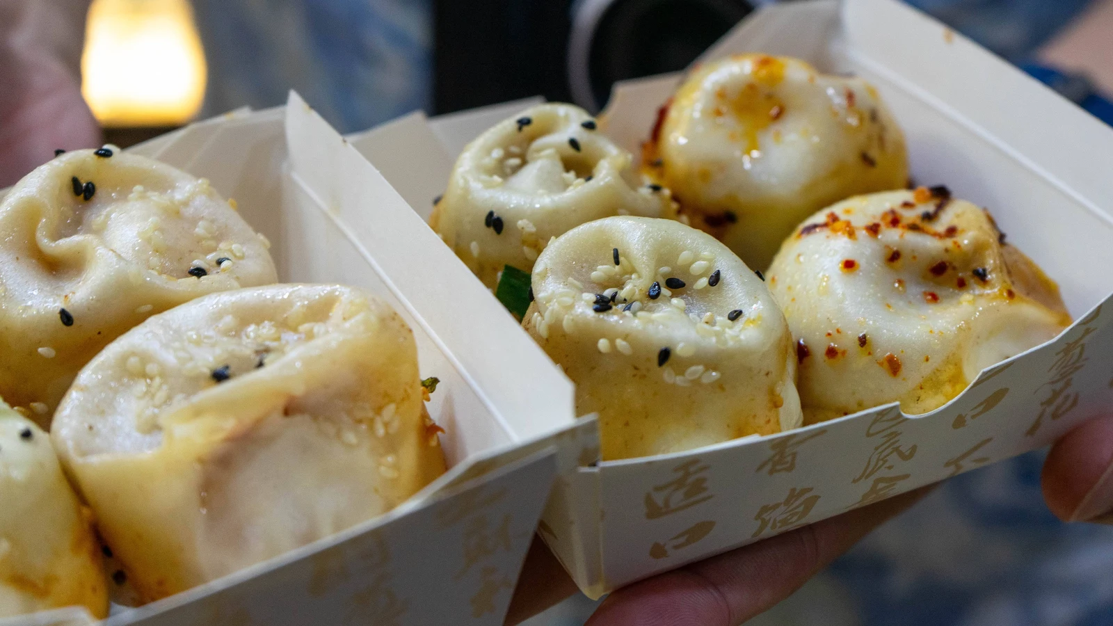 Golden pan-fried shengjian buns topped with sesame and spring onion