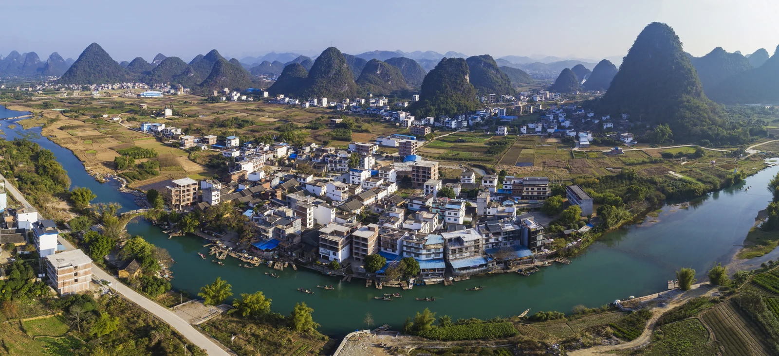 A river bends around fields and a village among Yangshuo’s karst peaks