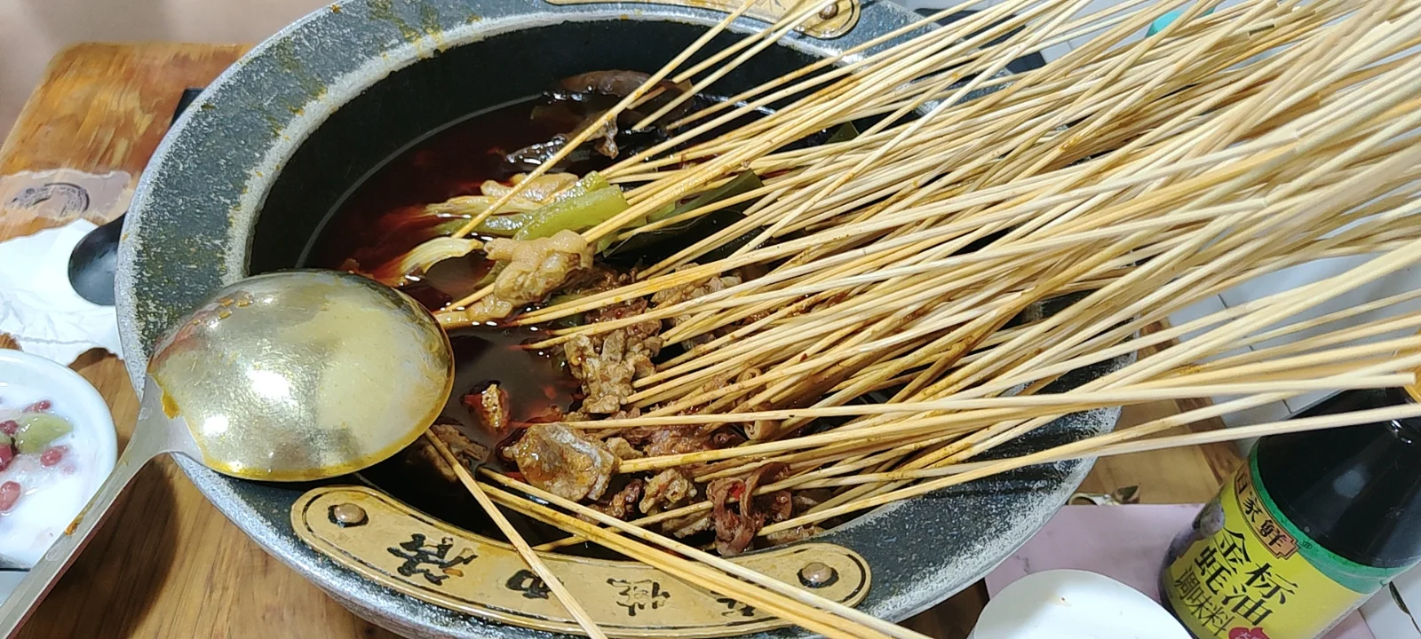 Bamboo skewers soaking in red chili broth for bobo chicken